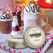 Hot chocolate with whipped cream and candy canes, peppermint mocha candle, and candy canes on a festive background.