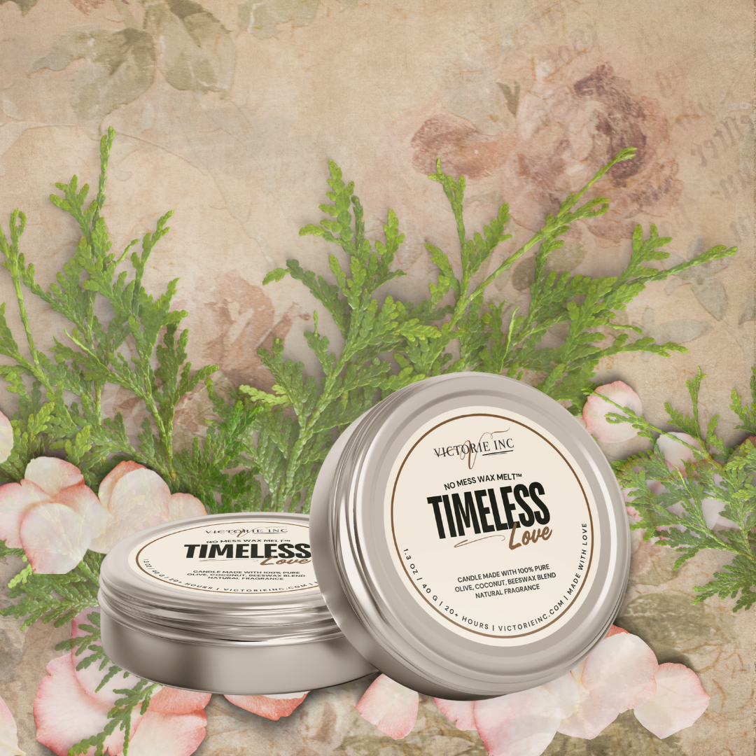Two 'Timeless Love' candles in tins on a decorative background with greenery and flowers.
