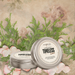 Two 'Timeless Love' candles in tins on a decorative background with greenery and flowers.